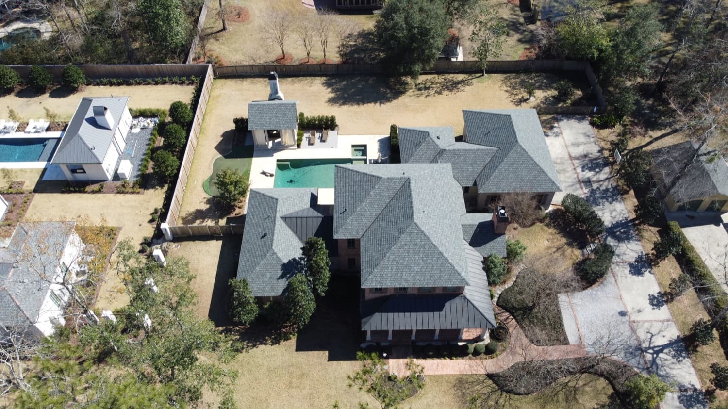 Brick estate with a new architectural shingle roof and poolside grounds